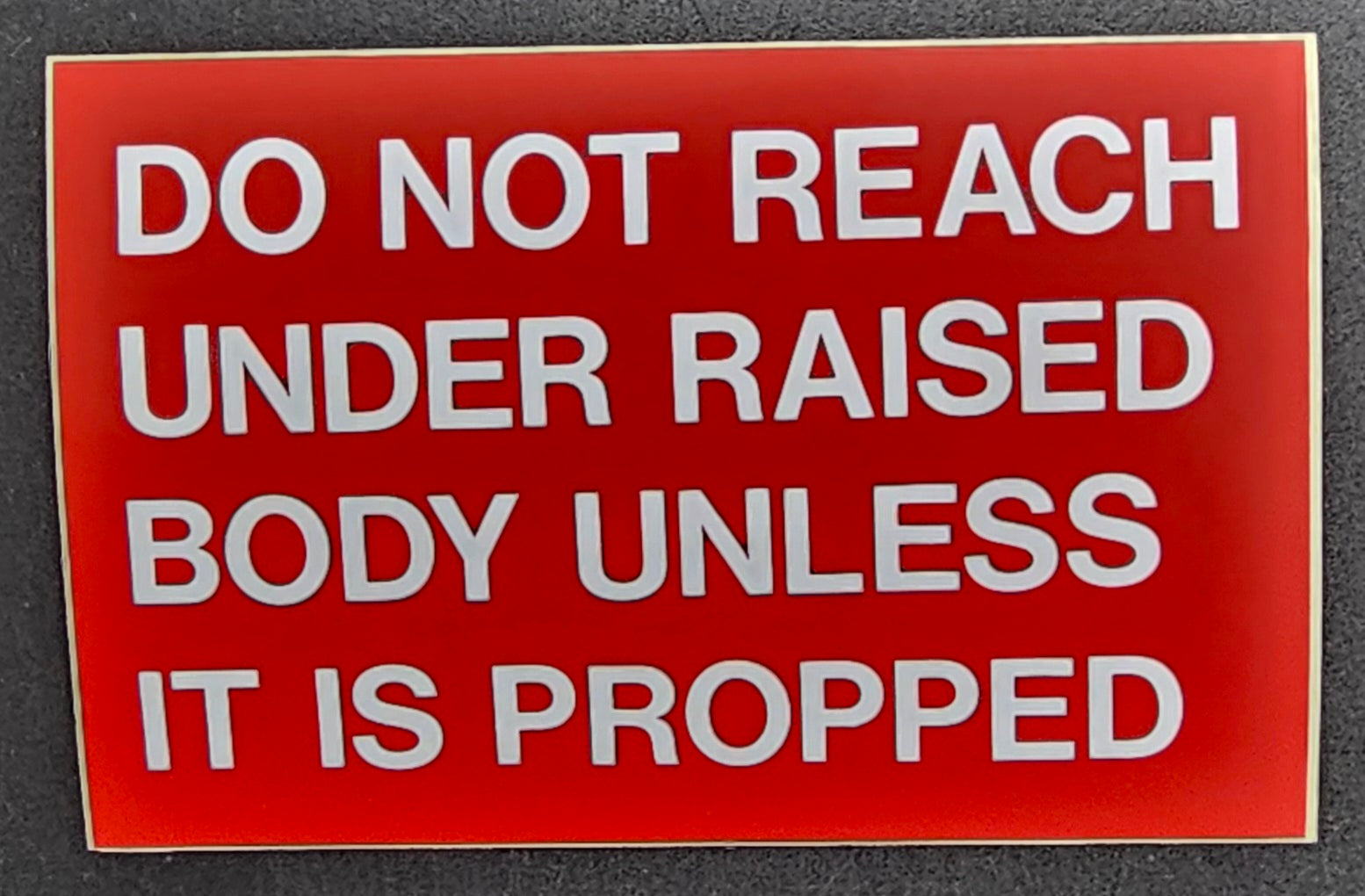 226. DO NOT REACH UNDER RAISED BODY UNLESS IT IT PROPPED (STICKER)